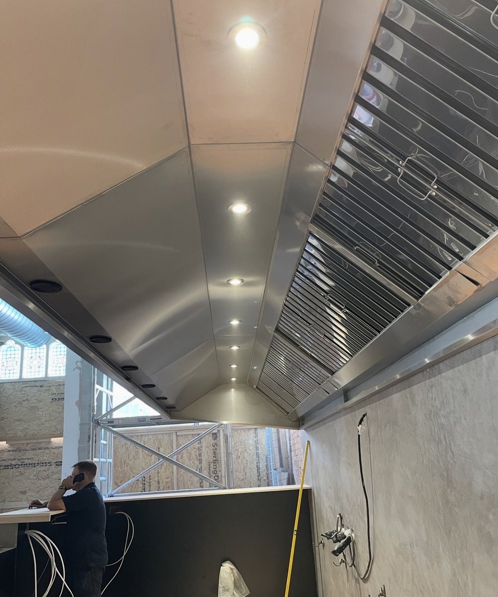 Bespoke wall-hung stainless steel extraction canopy with integrated lighting installed by Castle Catering Engineers