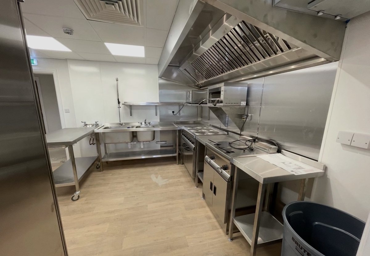 Completed commercial kitchen with wall-mounted extraction canopy, range and electrical suite by Castle Catering Engineers