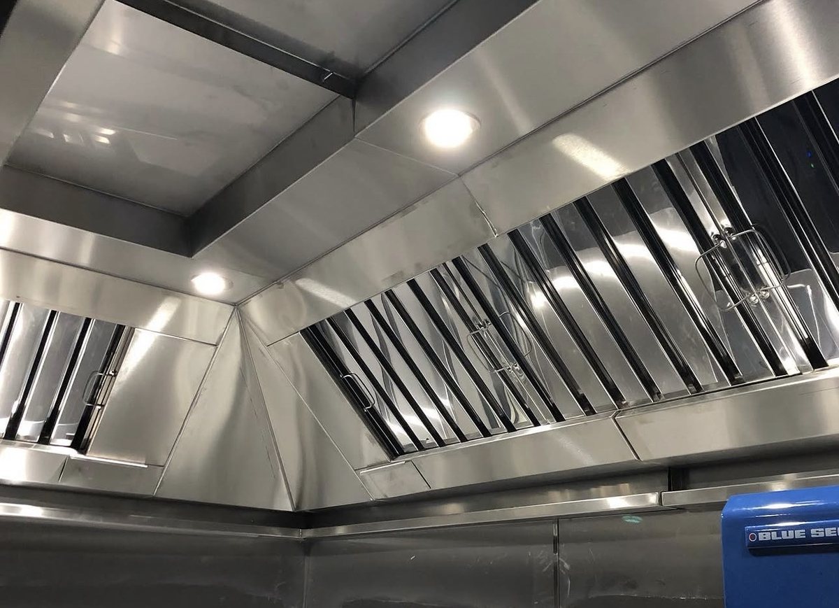 Stainless steel extraction canopy detail with baffle filters and recessed downlights over Blue Seal cooking equipment, Castle Catering Engineers