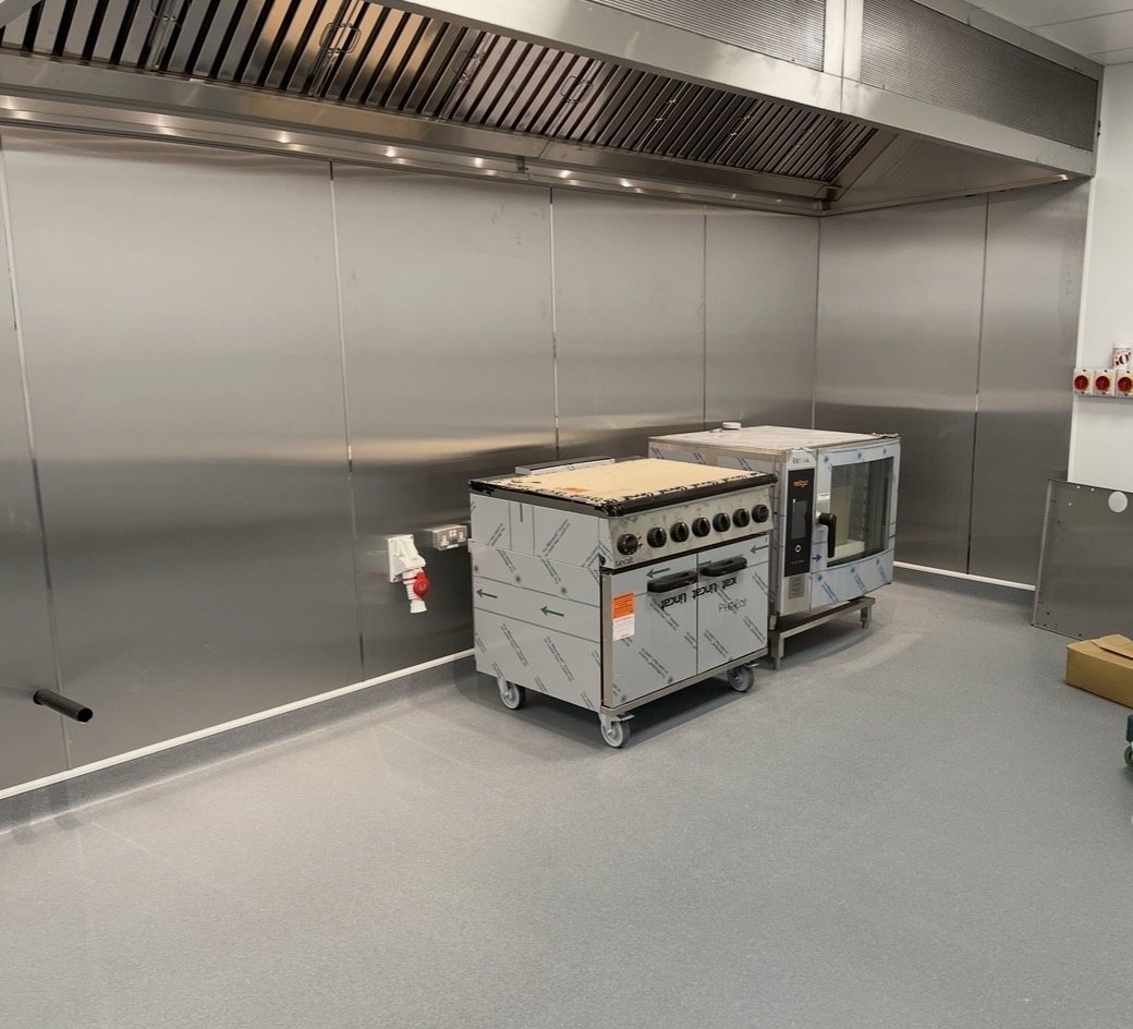 Wall extraction canopy with full stainless steel wall cladding and a new combination oven and range installed by Castle Catering Engineers