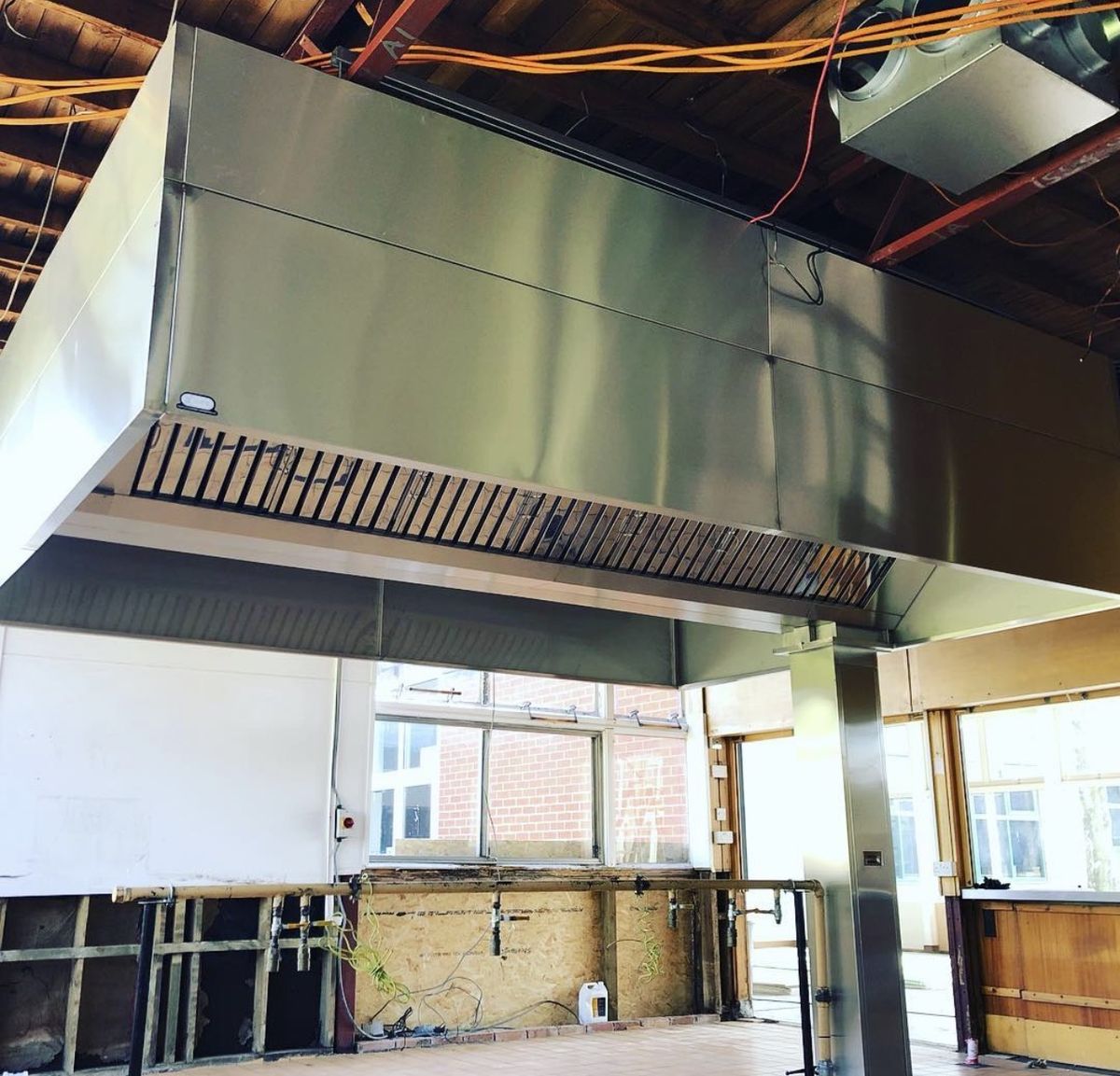 Large wall-mounted extraction canopy with integrated supply-air unit installed in a school kitchen by Castle Catering Engineers