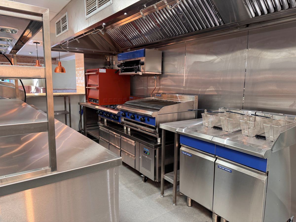 Main kitchen — Blue Seal cooking suite, charbroiler, fryer station and extraction canopy