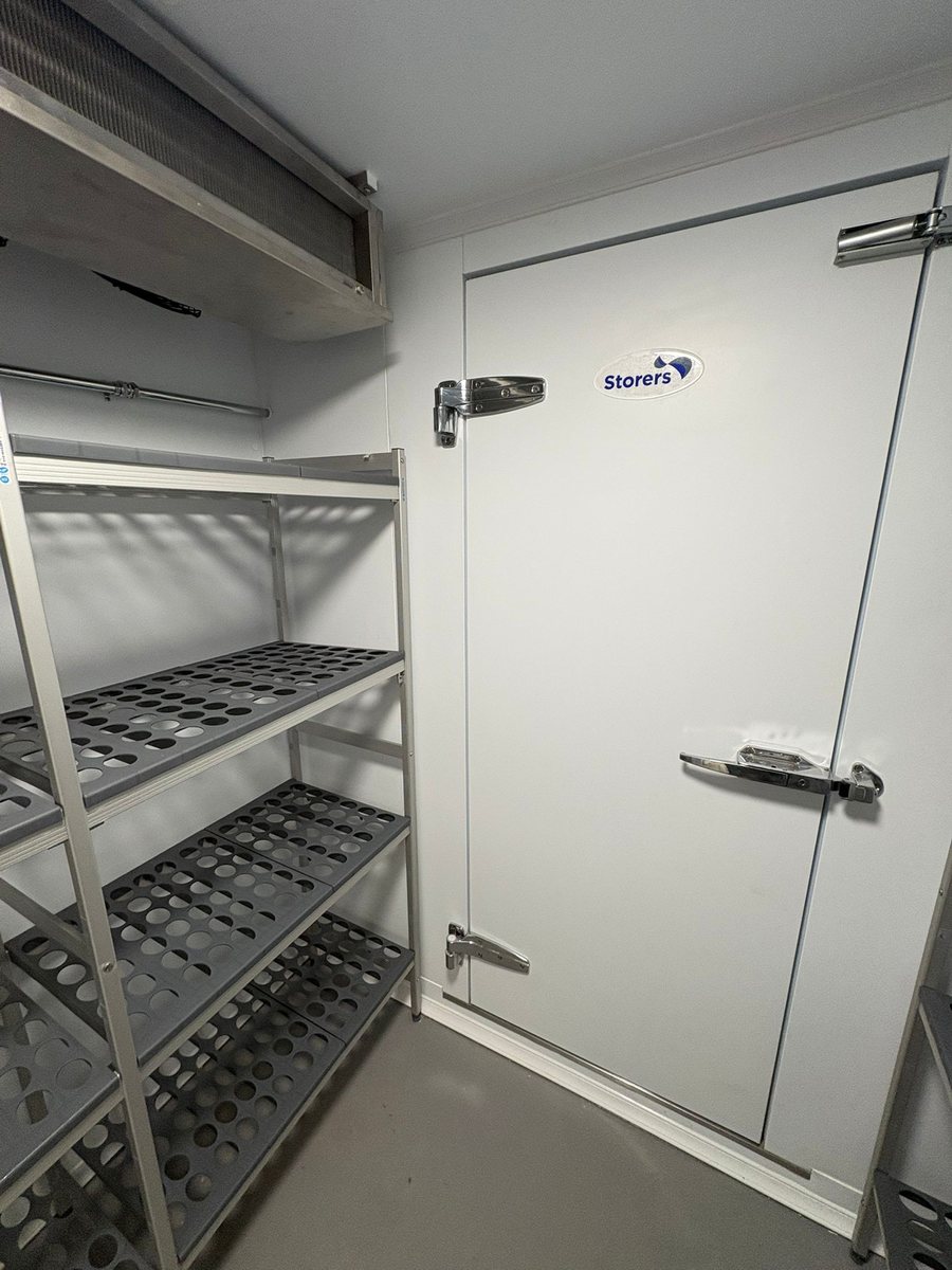 Cold room interior showing aluminium racking, perforated shelving and insulated door by Castle Catering Engineers
