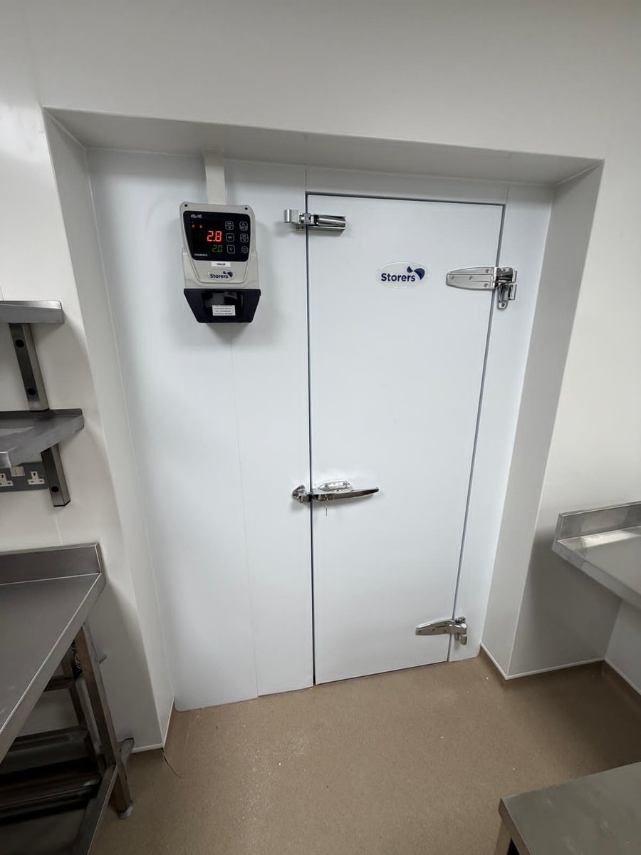 Storers walk-in chiller door with digital temperature controller in a stainless steel commercial kitchen